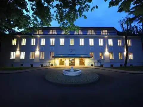 Elegantes Hotelgebäude in der Dämmerung mit Beleuchtung, das den Silvesterball im Lucas-Cranach-Saal ankündigt, mit Livemusik und Galabuffet im Hotel DER LINDENHOF.