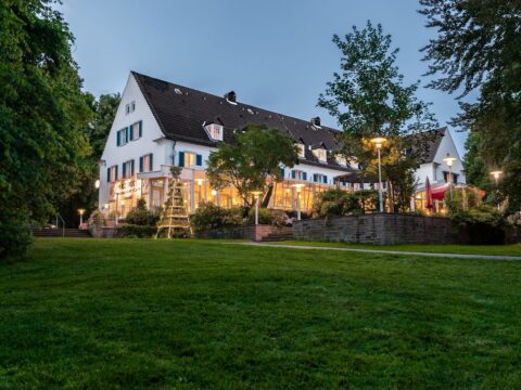 Das Parkhotel Wolfsburg festlich erleuchtet zur Silvesternacht, umgeben von grünen Gärten.