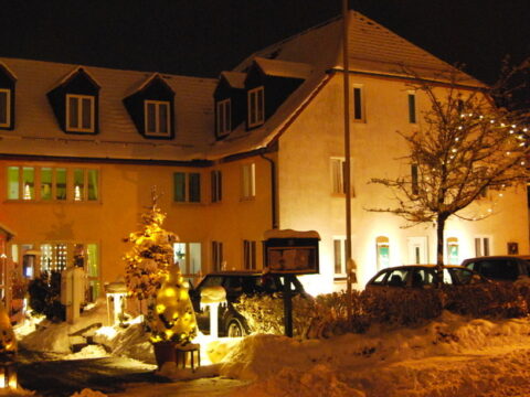 Schneebedecktes Hotel Residenz Leipzig bei Nacht, festlich beleuchtet zu Silvester